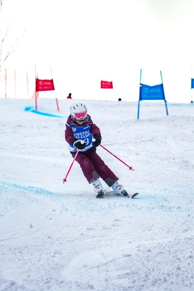 A U10 racer carving between giant slalom gates at an away race at Gunstock