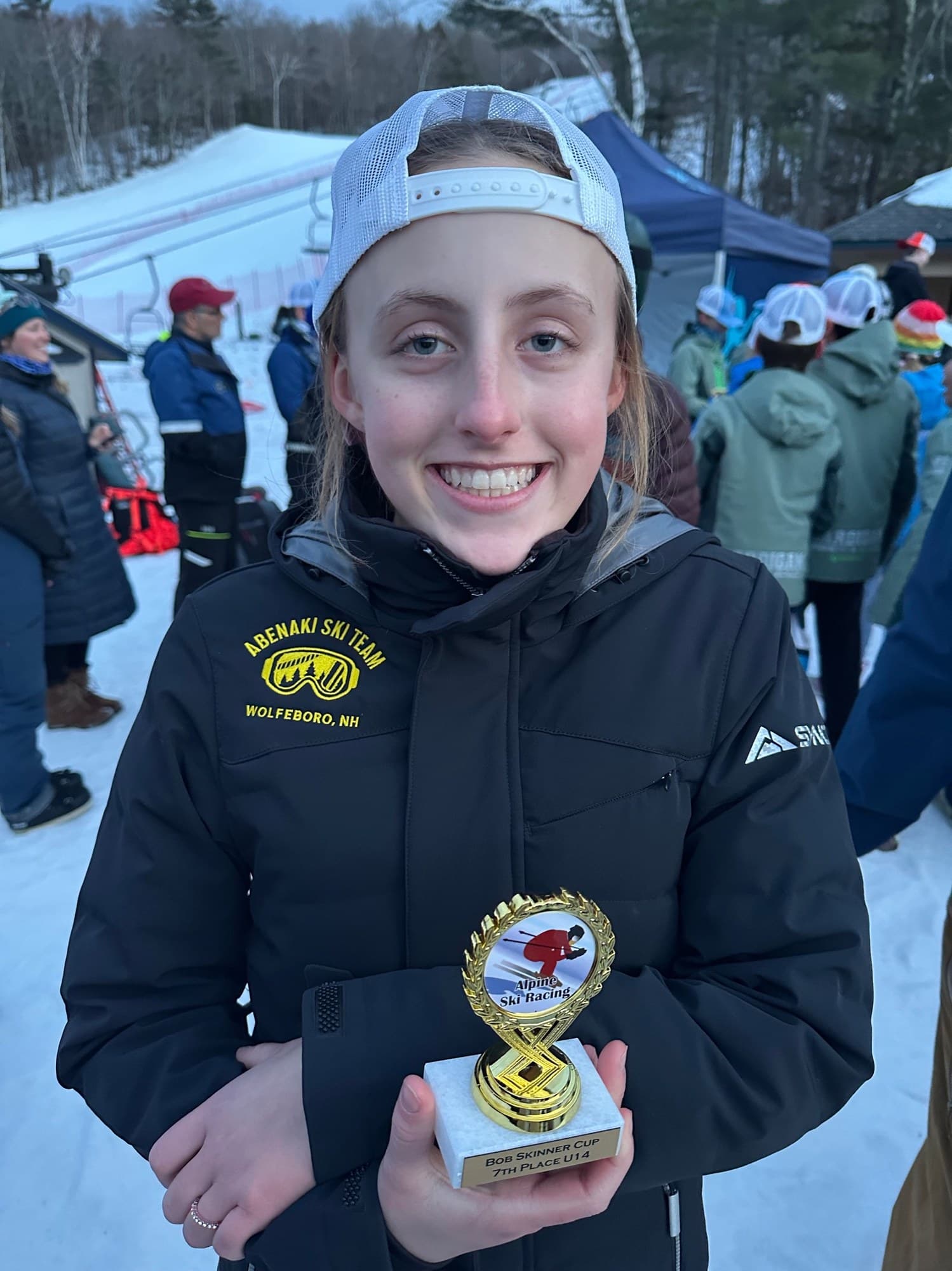 A U14 racer in an Abenaki Ski Team jacket holding a Bob Skinner Cup trophy