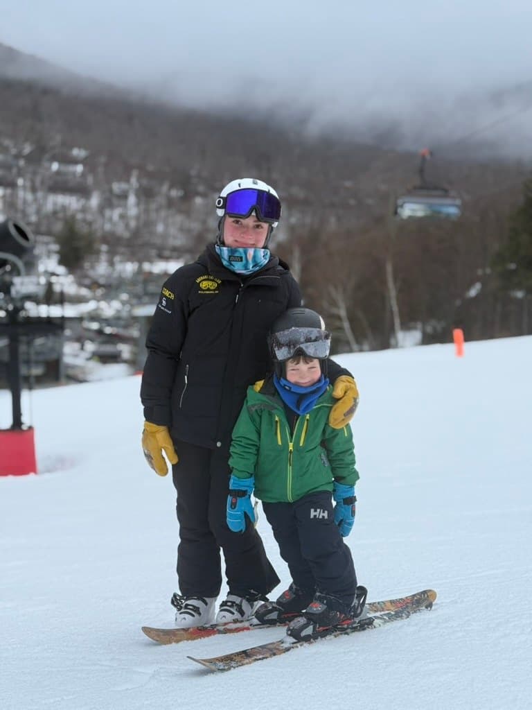 An Abenaki coach with an arm around a young skier on their first runs