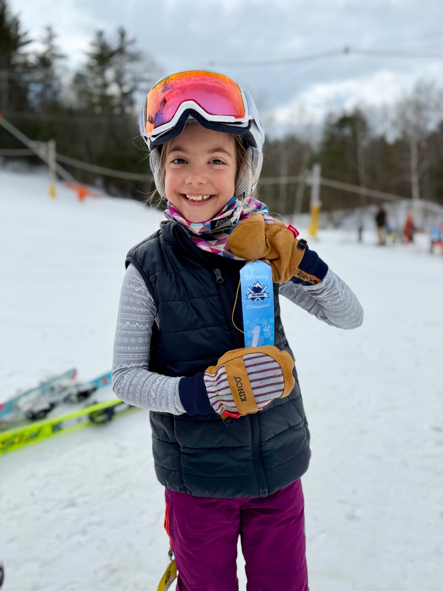 A U8 skier holding up a first-place Winter Carnival ribbon