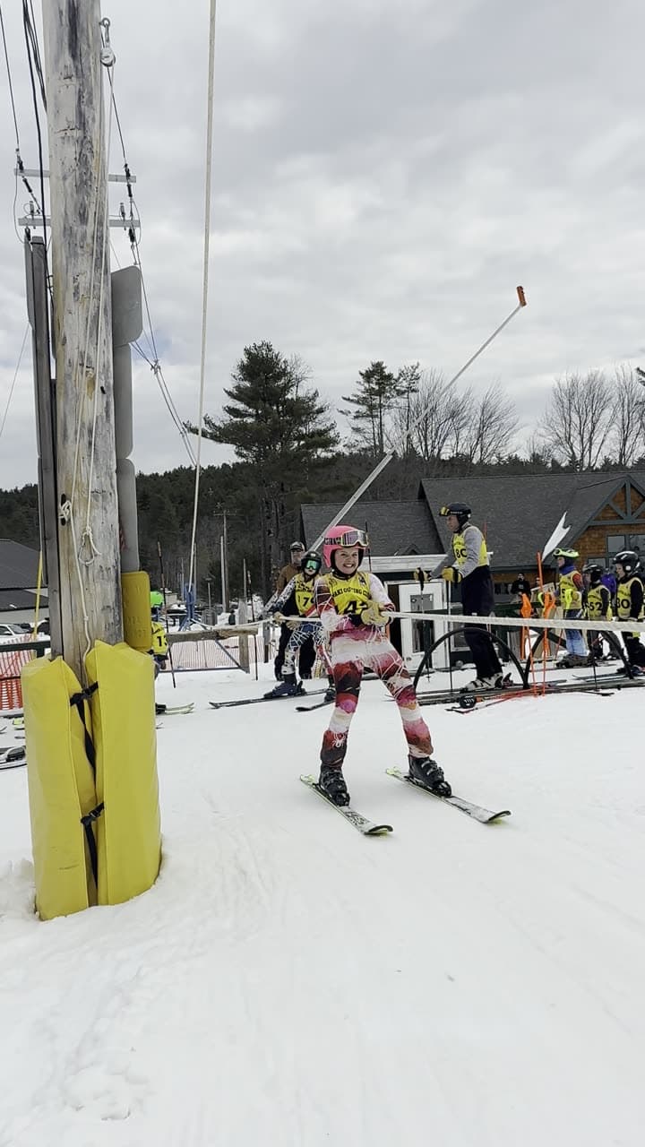 Kids riding the rope tow at Abenaki one after another: two snowboarders up the line with the lodge behind, racers in bibs passing the padded tower on race morning with teammates waiting behind the fence, a small skier close to the camera, and three more riding up at dusk with the lights on, one of them waving