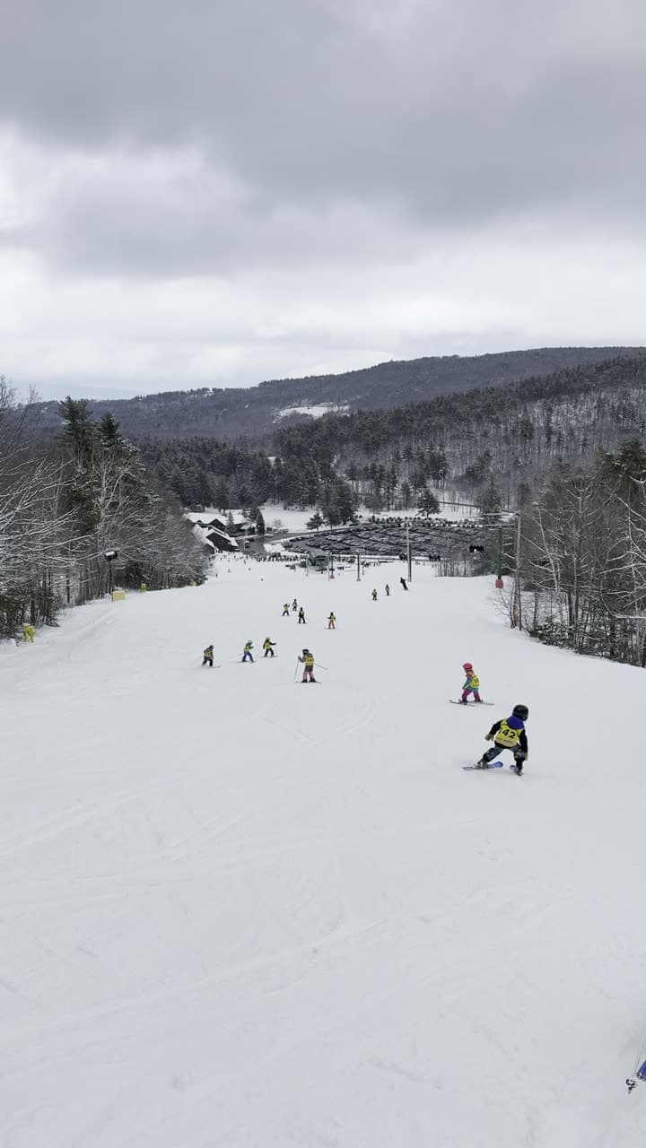 A group of U8 athletes skiing down the main slope together